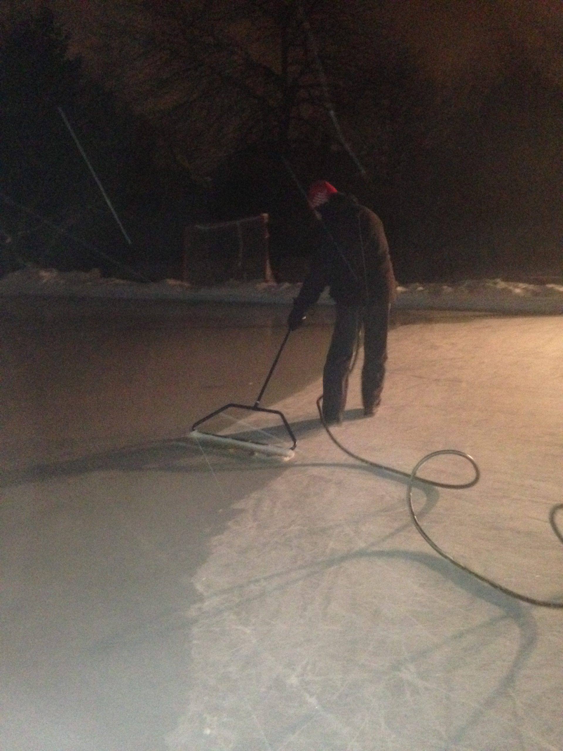 RinkWatch participant flooding a backyard rink at night